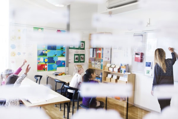 Classroom in session with students and teacher engaged in activities